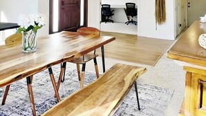 A dining area with a wooden table and benches, a vase with flowers, and a chandelier. - The Grove. Blackfoot. Spacious 4BR. Sleeps 16+  Retreat By Yellowstone (Blackfoot)