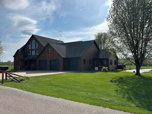 Een blokhut met twee verdiepingen, een puntig zadeldak, een veranda en een grote garage.