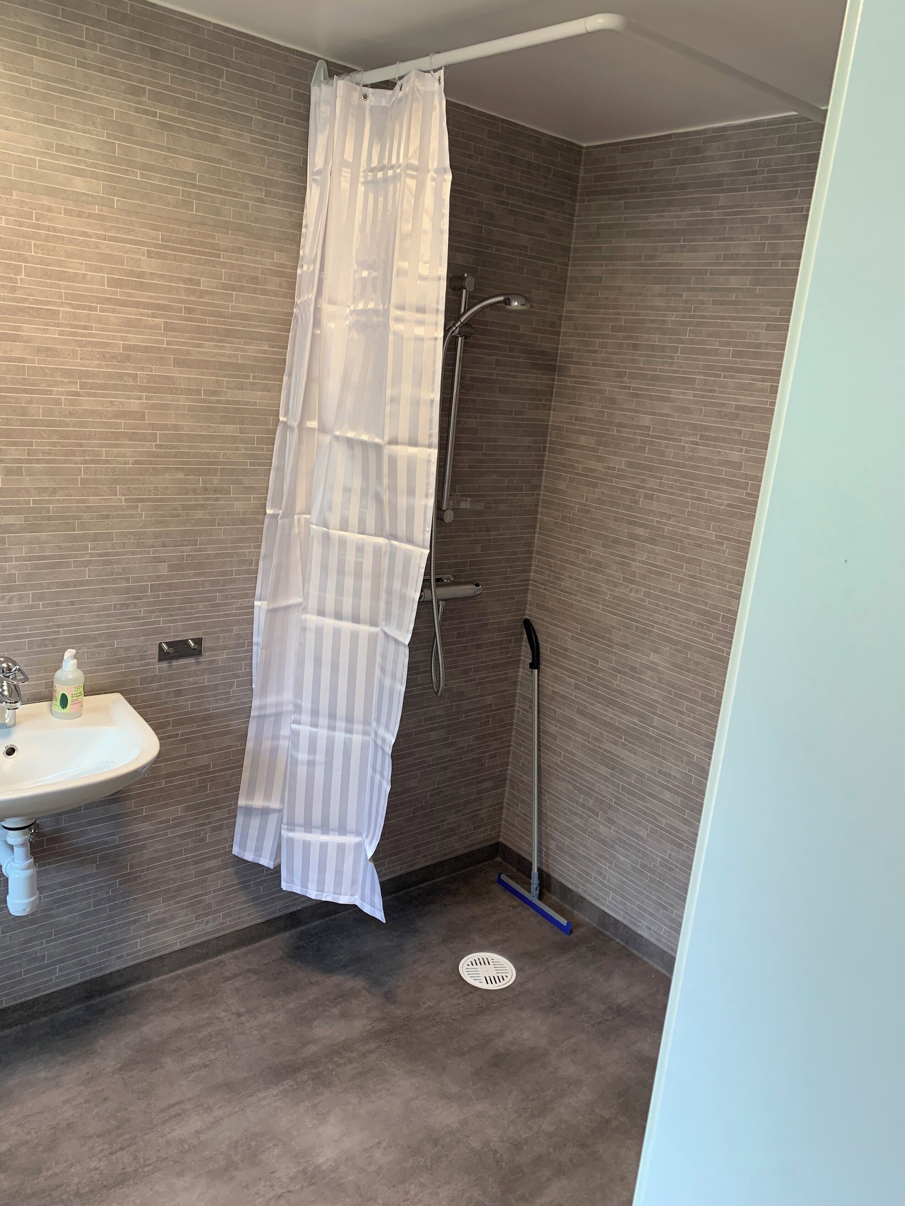 Een douche, handdoeken, zeep, toiletpapier