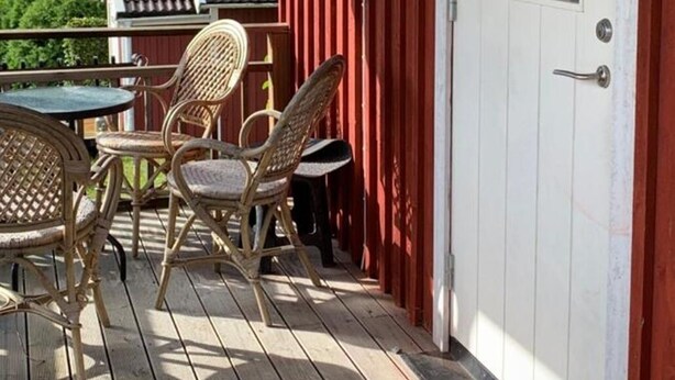 A wooden deck with wicker furniture and a white door. - Gårdshus1, live the country only 6 miles from Gothenburg, 5 miles from Ullared and Varberg. (Örby)