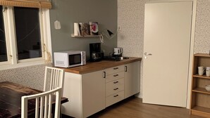 A compact kitchen with a microwave, coffee maker, and toaster on the counter, a dining table with chairs, and a striped rug on the floor. - Gårdshus1, live the country only 6 miles from Gothenburg, 5 miles from Ullared and Varberg. (Örby)