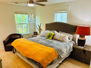Ein Schlafzimmer mit einem Bett, einem Sessel, einer Lampe und einem Fenster.