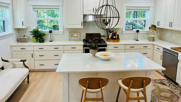 A modern kitchen with white cabinets, a central island, two bar stools, and a chandelier. - Coastal Retreat Minutes to Sullivans Island and downtown Charleston (Mount Pleasant)