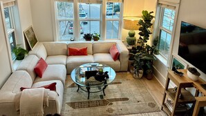 A living room with a sofa, a glass coffee table, and a TV. - Coastal Retreat Minutes to Sullivans Island and downtown Charleston (Mount Pleasant)