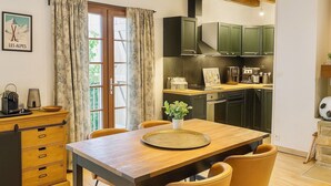 Cuina moderna amb armaris de fusta, una taula de dinar amb caires i una finestra amb cortines.
