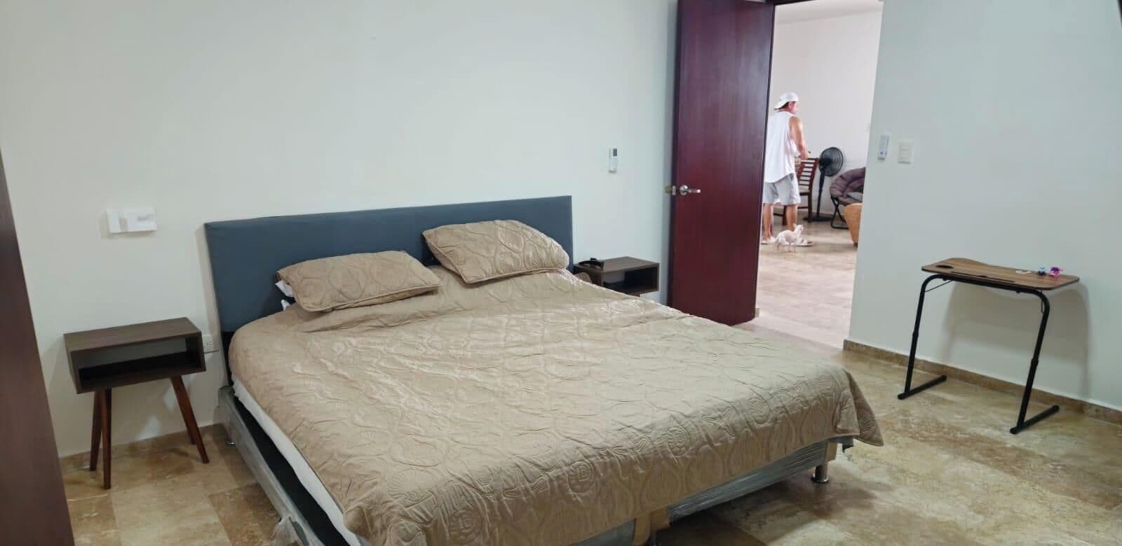 Une chambre à coucher comprenant un lit, une table de chevet, une petite table et une porte donnant sur une autre pièce.