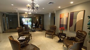 A spacious lobby with a chandelier, leather armchairs, and a tiled floor. - Comfortable and fully equipped apartment in the heart of Jardins. (São Paulo)
