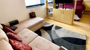 A modern living room with a sofa, a TV, and a wooden cabinet. - Comfortable and fully equipped apartment in the heart of Jardins. (São Paulo)