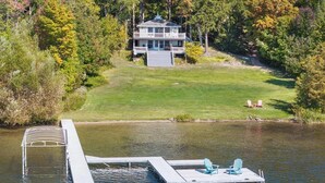 A lakeside house with a dock and chairs. - Charming bungalow on Walloon Lake. Close to Petoskey, ski areas, hiking & biking (Petoskey)