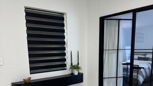 A modern room with a black-framed window, a black floating shelf with decorative items, and a view through a glass door to another room. - Newly renovated top to bottom Beautiful 2-bedroom house (Pompano Beach)