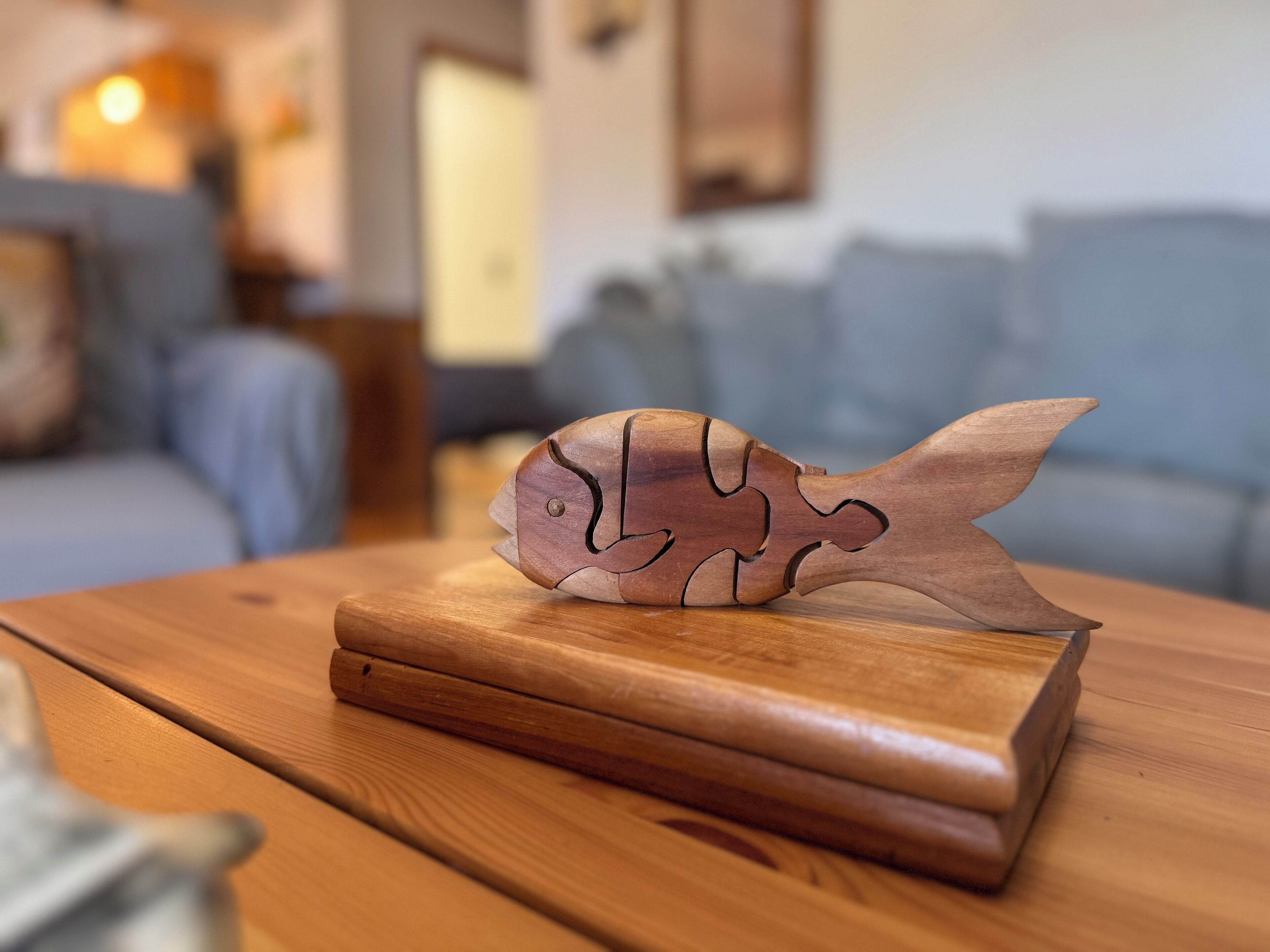 A wooden fish sculpture on a wooden table in a living room.