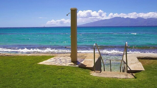 A coastal view with a grassy area, a concrete structure, and a clear blue sky. - I B-Garden View with Ocean Front BBQ/Pool/Jacuzzi (Lahaina)
