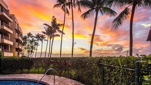 A swimming pool with a stone border, surrounded by palm trees and a sunset view. - I B-Garden View with Ocean Front BBQ/Pool/Jacuzzi (Lahaina)