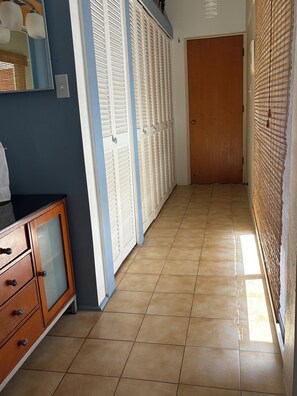 A hallway with a wooden cabinet, white louvered closets, and a wooden door at the end. - Book a getaway by 9/30/26 for 11/2026 and Receive a gift upon check-in! (St Thomas, USVI)