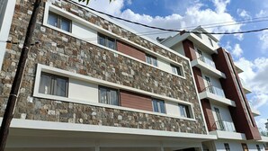A multi-story building with a stone facade, multiple balconies, and large windows. - Modern 2-Bedroom Apartment Near La Croisette, Grand Baie (Grand Baie Heights)