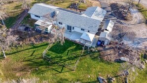 Ein zweigeschossiges Haus mit einem geneigten Dach, einem umzäunten Garten und einer kleinen Auffahrt.