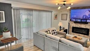 Een moderne woonkamer met een hoekbank, een flatscreen televisie en een open haard.