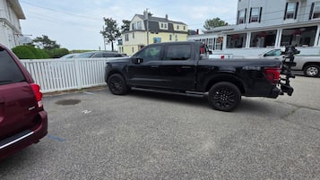 A parking lot with a black pickup truck and a maroon SUV.