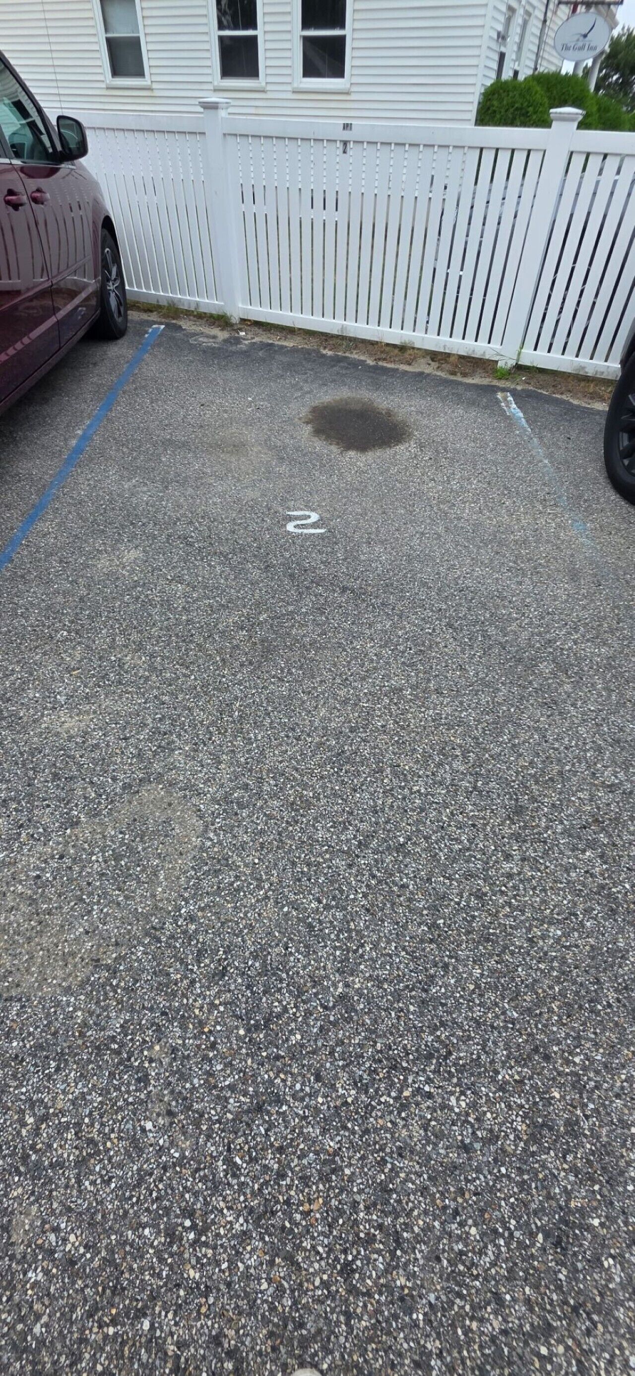 Un estacionamiento con cerca blanca y un edificio al fondo.