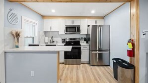 A modern kitchen with white cabinets, stainless steel appliances, and a wooden ceiling. - Charming Beachfront Loft | New Renovation (Old Orchard Beach)