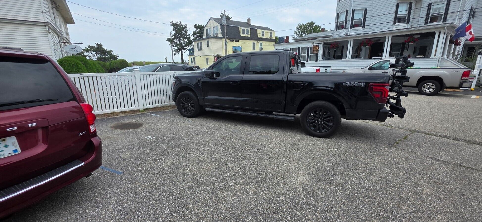 A parking lot with a black pickup truck and a maroon SUV.