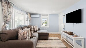 En moderne stue med en sofa, et fjernsyn og et vindue med gardiner.