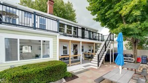 Et toetagers hus med balkon, trappe og en patio med udendørs møbler.