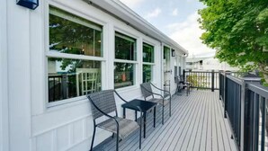 Eine überdachte Terrasse im Freien mit Geländer, zwei Stühlen und einem Tisch.