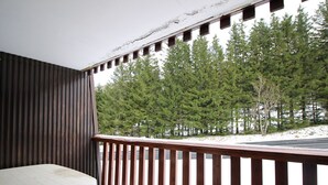 En balkon med gelænder af træ, et hvidt bord og en stol.