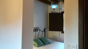 A bedroom with a bed, green pillows, a dark headboard, a hanging light fixture, and a wooden ceiling. - Historic Studio in Granada, Near Alhambra (Granada)