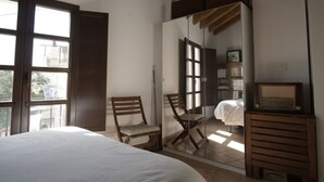 Quarto com cama, cadeiras de madeira, guarda-roupa e espelho.