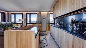 Una cocina moderna con armarios de madera, encimera negra y vistas a la montaña a través de amplias ventanas.