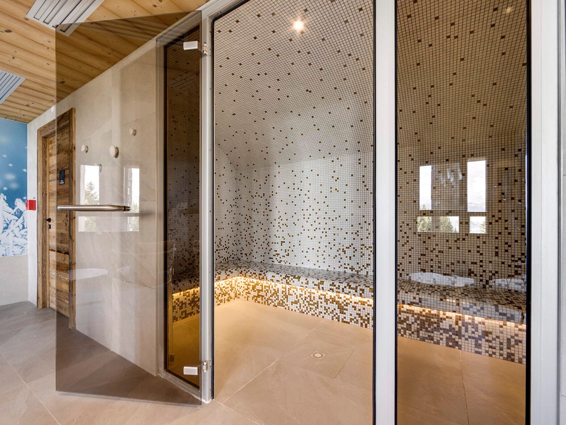 Een moderne badkamer met een wand van mozaïektegels, een glazen douchecabine en een houten plafond.