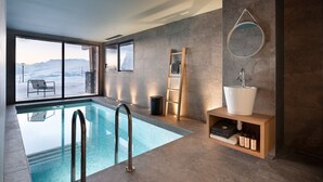 A modern bathroom with a large window, a bathtub, a sink, and a shelf with bottles. - Luxury chalet in Les Arcs 1800 with indoor pool and home cinema (Les Arcs 1800)