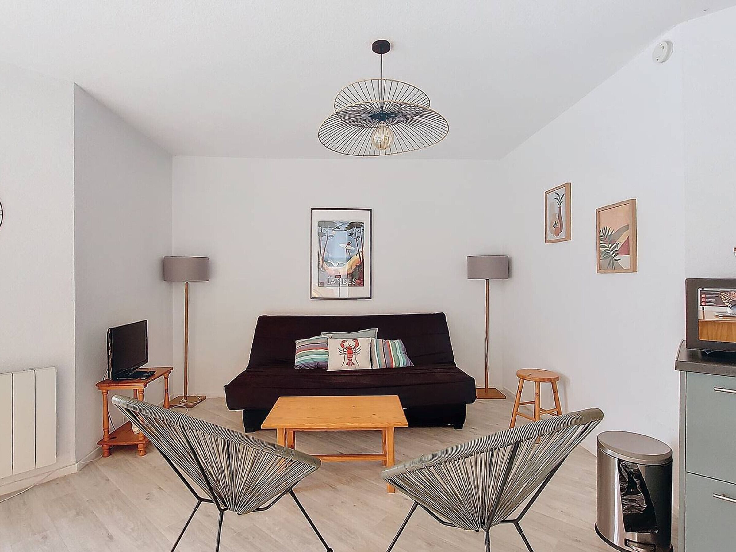 Een moderne woonkamer met een donkere bank, twee fauteuils, een houten salontafel en een hanglamp.