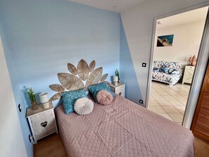A bedroom with a bed, nightstands, and a wall with a leaf design. - Family apartment near the beach with parking (Fleury-Saint-Pierre-la-Mer)
