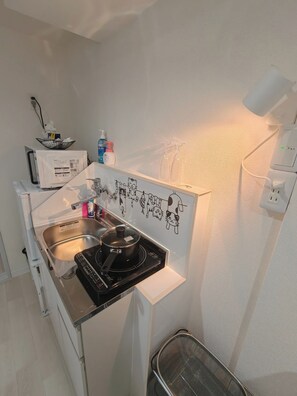 Een koelkast, een magnetron, kookgerei, borden en bestek