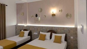 A hotel room with two beds, a ceiling fan, and decorative wall sconces. - Reluxmee Hotel Anuradapura (Anuradhapura)