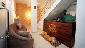 A reception area with a wooden desk, a sofa, and a staircase. - Reluxmee Hotel Anuradapura (Anuradhapura)