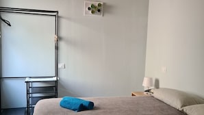 Quarto com cama, escrivaninha, luminária pendente e planta na parede.