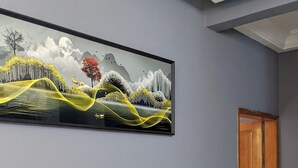 Ein Essbereich mit einem schwarzen Marmortisch, vier schwarzen Stühlen und einer Vase mit getrockneten Pflanzen. Über dem Tisch hängt ein großes Landschaftsbild an der Wand.