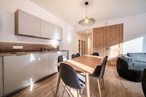 Eine moderne Küche mit Holztisch und -stühlen, einer Pendelleuchte und einem Holzkasten.