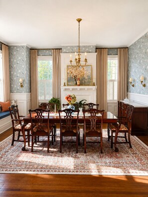 Ein Esszimmer mit einer Chandelüster, einem Kamin und einem großen Fenster.
