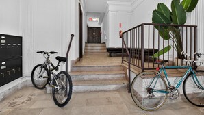 A staircase with a metal railing, a black bicycle, and a blue bicycle leaning against the railing.