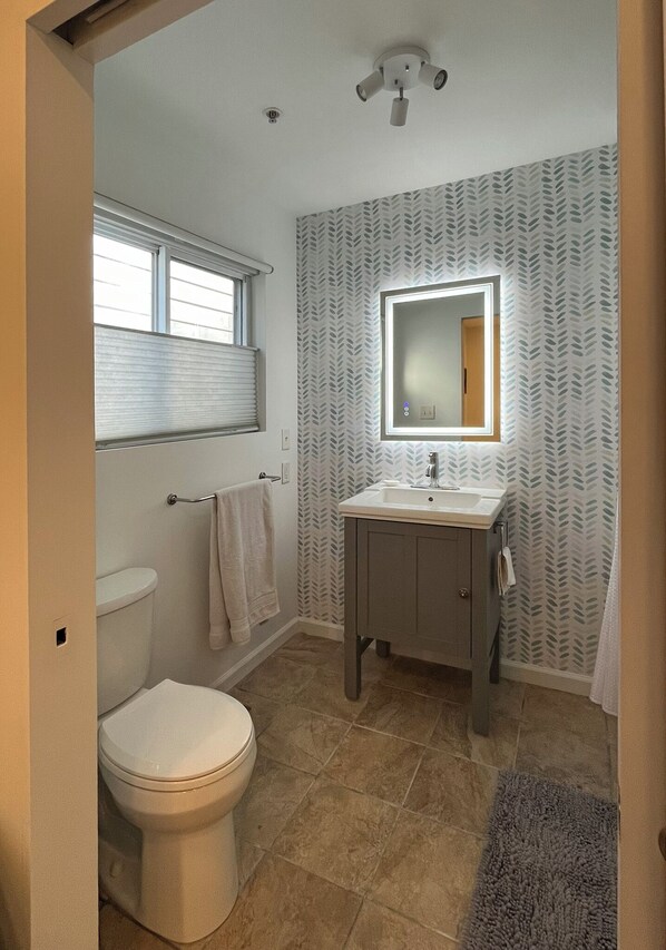 A bathroom with a toilet, sink, and mirror.