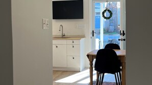 Uma cozinha moderna com armários brancos, forno embutido e uma TV de tela plana.