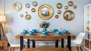 A dining room with a wooden table set for six, surrounded by white chairs. - River Heights With Views Parking By My Getaways (Shoreham-by-Sea)