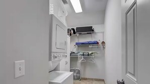 Une buanderie équipée d’un lave-linge, d’un sèche-linge et d’étagères où sont pliés les vêtements.