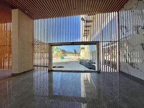 Un interior moderno con un amplio ventanal que da a un espacio exterior, suelo pulido y techo de listones de madera.