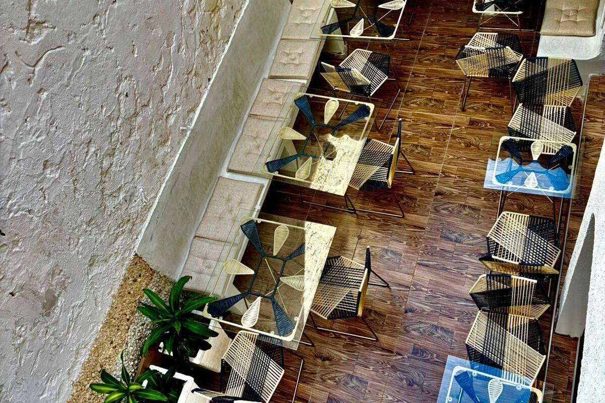 An outdoor seating area with multiple tables and chairs, a tiled floor, and potted plants.